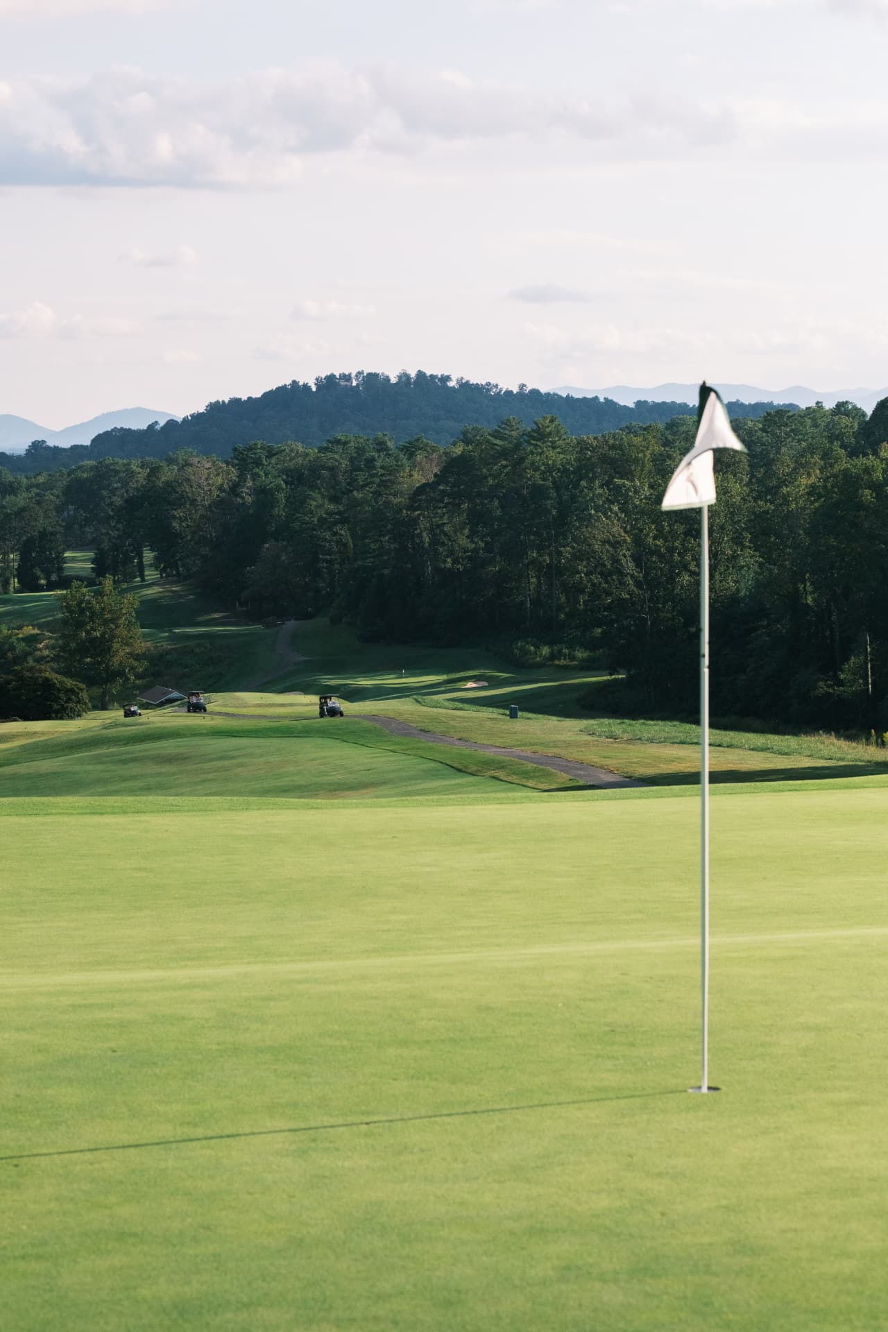 Golf course fairway with flagstick and rolling mountains in the distance
